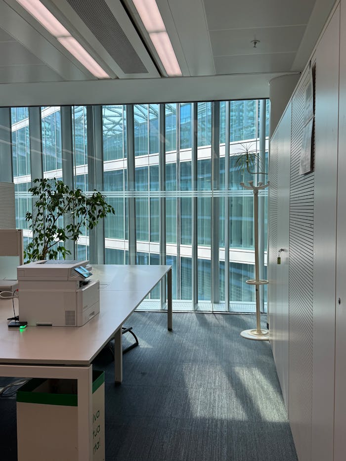 Bright office space in Milan featuring large windows, modern furniture, and natural lighting.