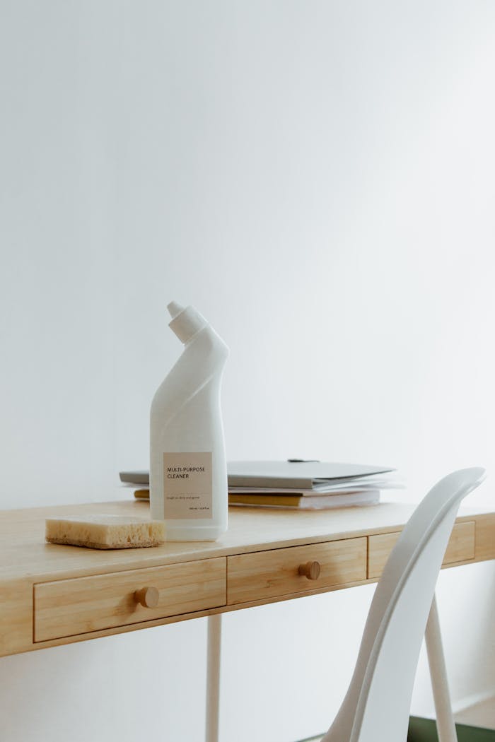 A clean and organized home office desk with a cleaner bottle and sponge, emphasizing simplicity and functionality.